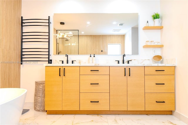 1149 SE Sandia Dr, Port St Lucie, FL 34983 - full bath with marble look tile flooring, double vanity, a freestanding bath, a towel warming rack, and recessed lighting