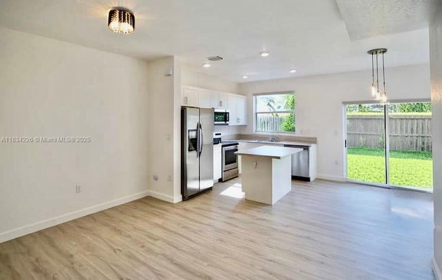 1589 SE 26th Rd, Homestead, FL 33035 - kitchen with stainless steel appliances, a kitchen island, light wood finished floors, white cabinets, and light countertops