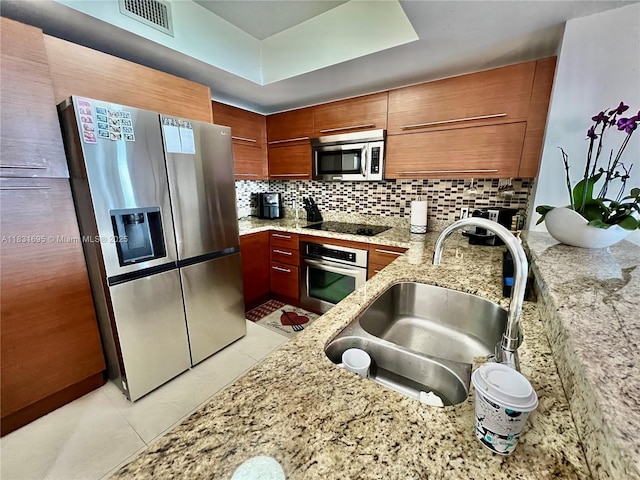 2641 N Flamingo Rd Unit 605N, Sunrise, FL 33323 - kitchen with appliances with stainless steel finishes, tasteful backsplash, light tile patterned flooring, light stone countertops, and brown cabinetry