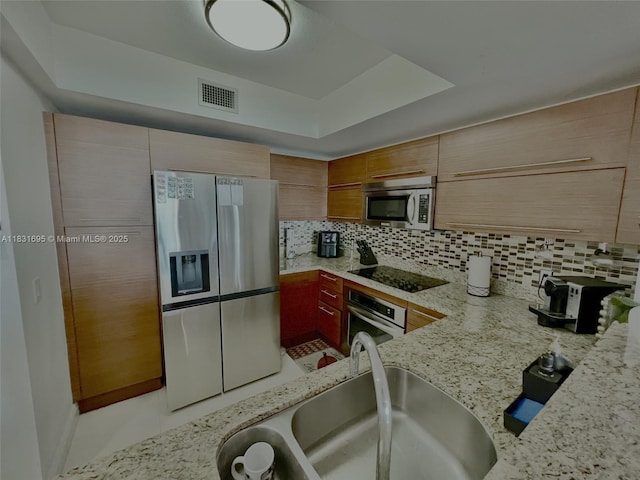 2641 N Flamingo Rd Unit 605N, Sunrise, FL 33323 - kitchen with stainless steel appliances, backsplash, a tray ceiling, and light stone countertops