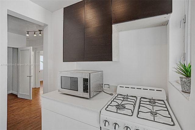 1616 Euclid Ave Unit 4, Miami Beach, FL 33139 - detailed view of stainless steel microwave, white gas stove, wood finished floors, light countertops, and dark brown cabinetry