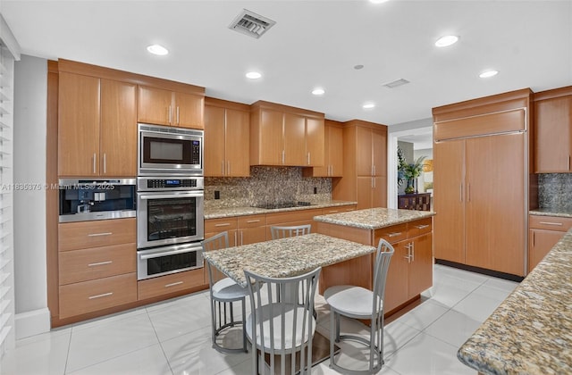 200 E Palmetto Park Rd Unit 714, Boca Raton, FL 33432 - kitchen featuring appliances with stainless steel finishes, a center island, a warming drawer, tasteful backsplash, and brown cabinetry