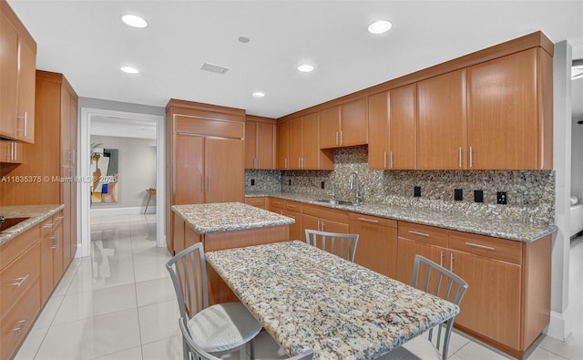 200 E Palmetto Park Rd Unit 714, Boca Raton, FL 33432 - kitchen featuring a kitchen island, tasteful backsplash, light stone counters, brown cabinets, and recessed lighting