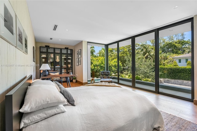 3910 Battersea Rd, Miami, FL 33133 - bedroom featuring a wall of windows, access to exterior, multiple windows, and wood finished floors