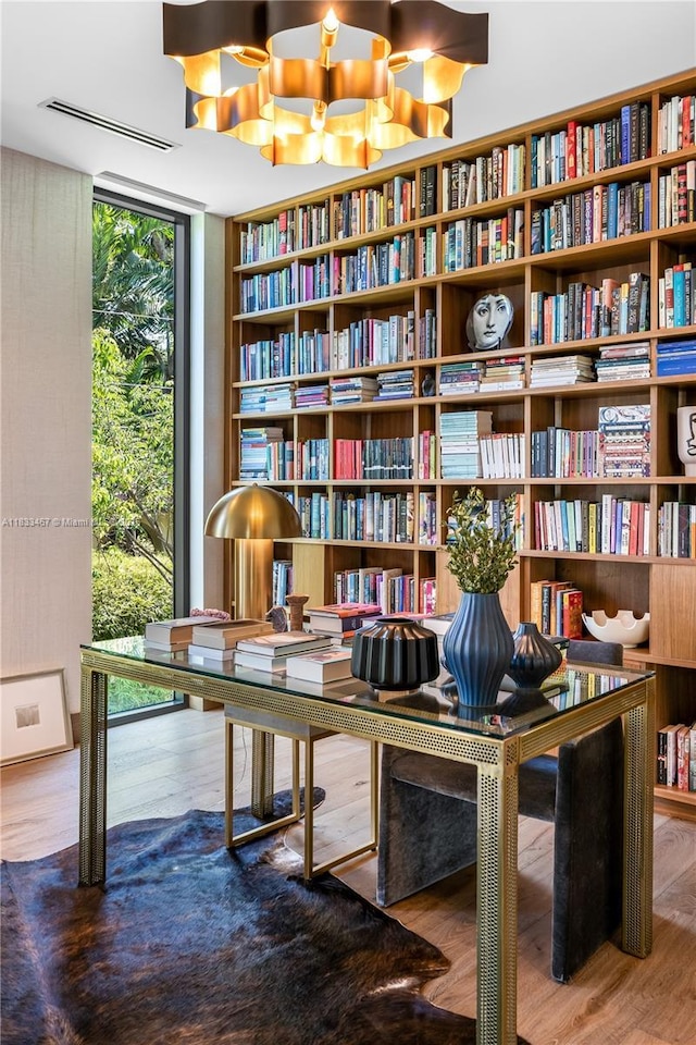 3910 Battersea Rd, Miami, FL 33133 - living area featuring bookshelves, a wall of windows, a chandelier, and wood finished floors