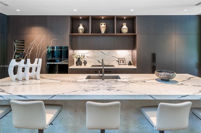 3910 Battersea Rd, Miami, FL 33133 - kitchen with backsplash, light stone counters, modern cabinets, a breakfast bar area, and recessed lighting