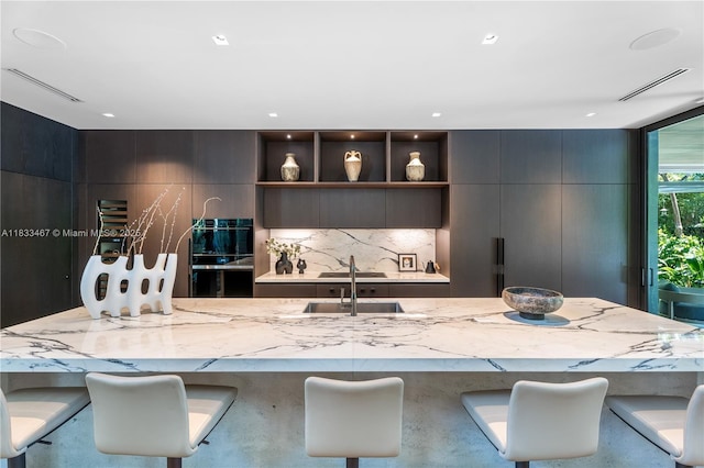 3910 Battersea Rd, Miami, FL 33133 - kitchen with modern cabinets, light stone counters, tasteful backsplash, and a kitchen bar