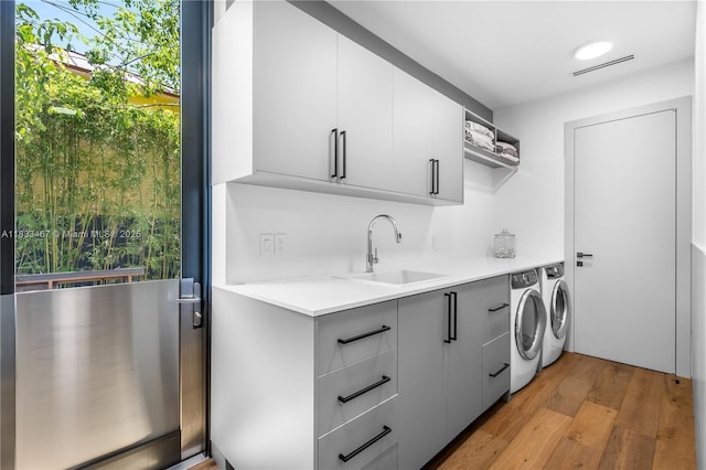 3910 Battersea Rd, Miami, FL 33133 - washroom featuring washing machine and dryer, cabinet space, light wood-style floors, and plenty of natural light