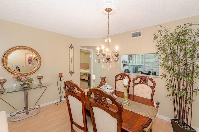 901 Colony Point Cir Unit 107, Pembroke Pines, FL 33026 - dining room featuring a chandelier, light wood finished floors, and a textured ceiling