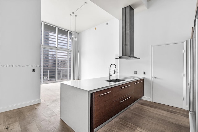 495 SE Brickell Ave Unit 1511, Miami, FL 33131 - kitchen featuring modern cabinets, wall chimney exhaust hood, dark brown cabinets, light countertops, and wood finished floors