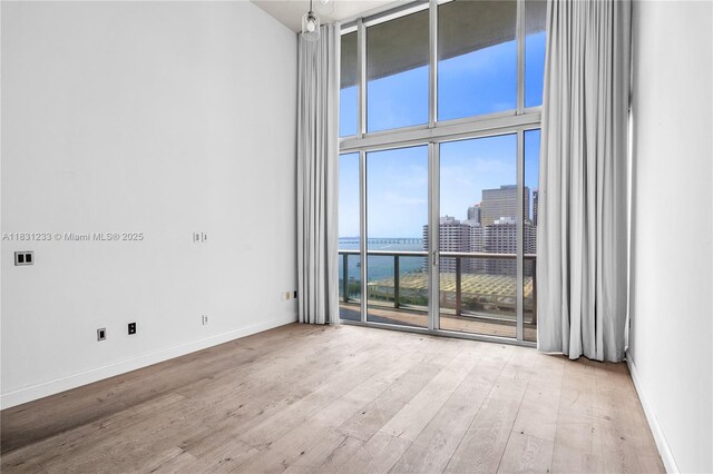 495 SE Brickell Ave Unit 1511, Miami, FL 33131 - empty room featuring wood finished floors, floor to ceiling windows, a high ceiling, a view of city, and a water view