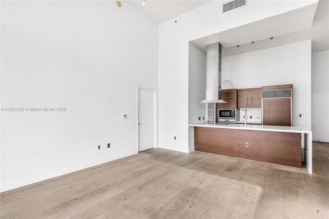 495 SE Brickell Ave Unit 1511, Miami, FL 33131 - kitchen featuring range hood, built in appliances, a high ceiling, light wood finished floors, and light countertops