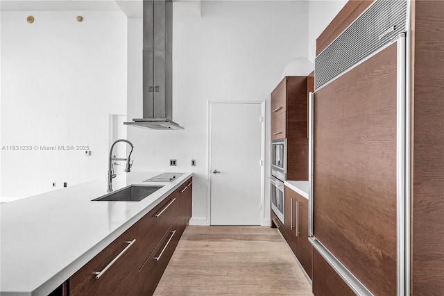 495 SE Brickell Ave Unit 1511, Miami, FL 33131 - kitchen featuring modern cabinets, island range hood, paneled built in refrigerator, light wood-type flooring, and light countertops