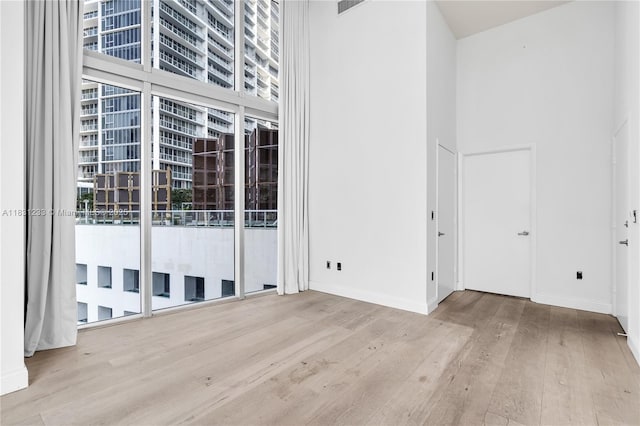 495 SE Brickell Ave Unit 1511, Miami, FL 33131 - spare room with wood finished floors, plenty of natural light, and a towering ceiling