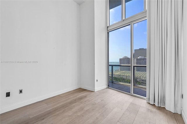 495 SE Brickell Ave Unit 1511, Miami, FL 33131 - spare room with light wood-style flooring, a city view, a towering ceiling, and floor to ceiling windows