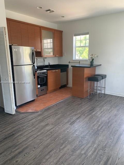 1244 Pennsylvania Ave Unit 306, Miami Beach, FL 33139 - kitchen featuring stainless steel appliances, dark countertops, wood finished floors, a breakfast bar, and recessed lighting