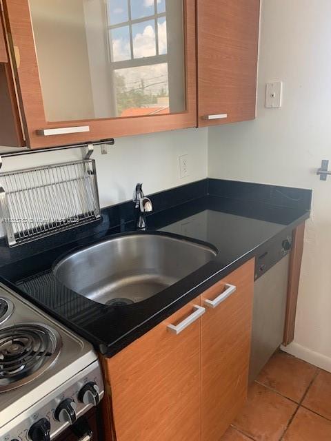 1244 Pennsylvania Ave Unit 306, Miami Beach, FL 33139 - kitchen featuring dark countertops, light tile patterned floors, stove, and stainless steel dishwasher