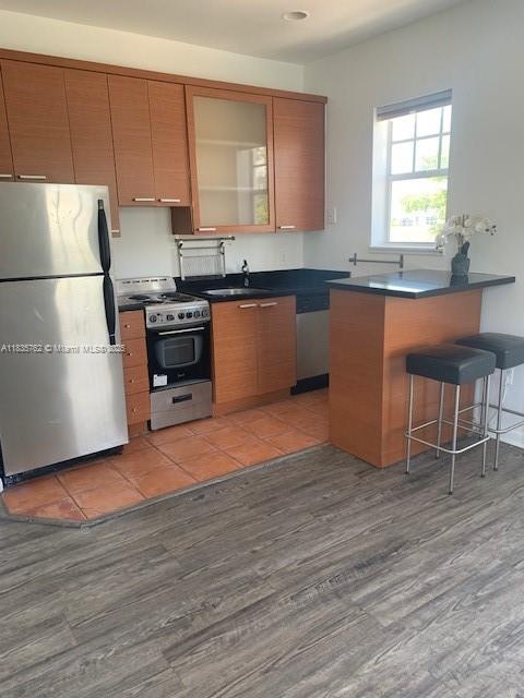 1244 Pennsylvania Ave Unit 306, Miami Beach, FL 33139 - kitchen with stainless steel appliances, dark countertops, light wood-style flooring, and a breakfast bar area