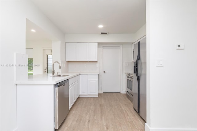 4516 Mainland Dr, Tamarac, FL 33319 - kitchen with stainless steel appliances, white cabinets, light wood-type flooring, a peninsula, and light countertops