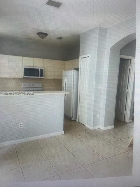 7325NW 174th Te # 104, Miami Lakes, FL 33015 - kitchen featuring stainless steel microwave, arched walkways, freestanding refrigerator, light countertops, and range