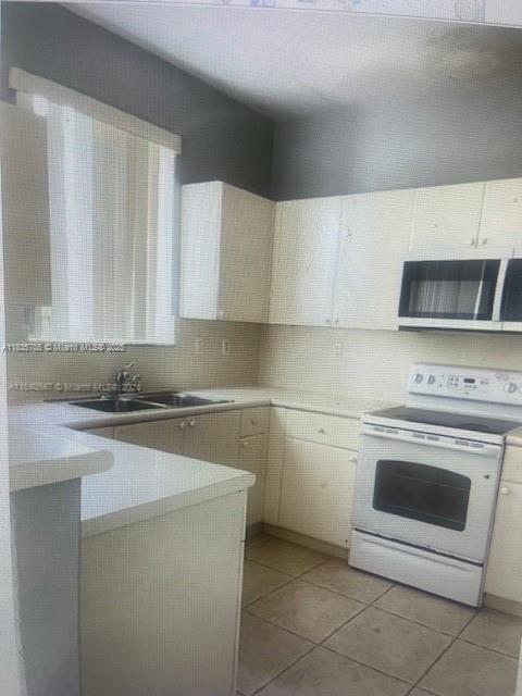 7325NW 174th Te # 104, Miami Lakes, FL 33015 - kitchen with white electric range, light tile patterned flooring, light countertops, and tasteful backsplash
