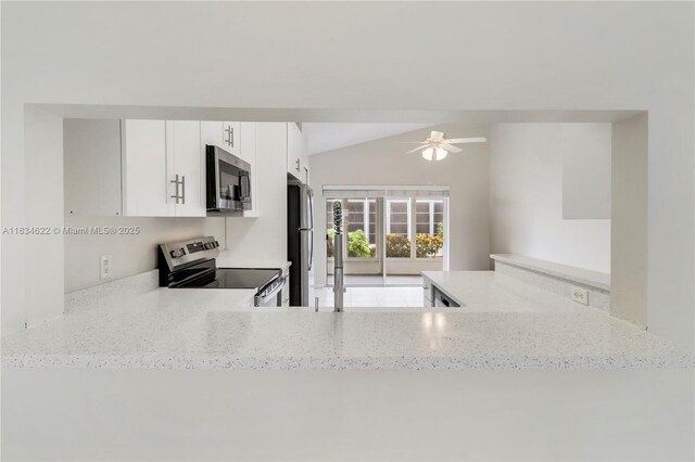 653 NW San Remo Cir, Port St Lucie, FL 34986 - kitchen with stainless steel appliances, vaulted ceiling, light stone countertops, ceiling fan, and white cabinets