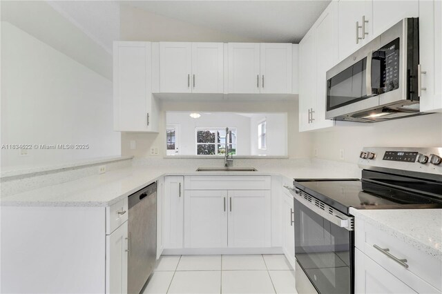 653 NW San Remo Cir, Port St Lucie, FL 34986 - kitchen featuring appliances with stainless steel finishes, white cabinetry, light tile patterned floors, lofted ceiling, and light stone counters