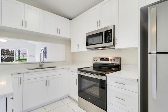 653 NW San Remo Cir, Port St Lucie, FL 34986 - kitchen with stainless steel appliances, white cabinets, light tile patterned flooring, light stone countertops, and ceiling fan