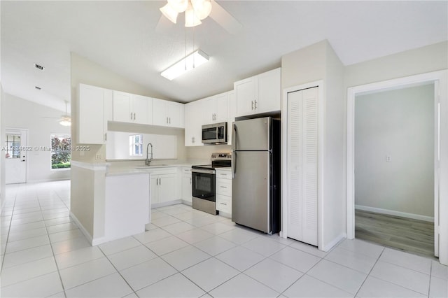 653 NW San Remo Cir, Port St Lucie, FL 34986 - kitchen with stainless steel appliances, a ceiling fan, light countertops, vaulted ceiling, and white cabinetry