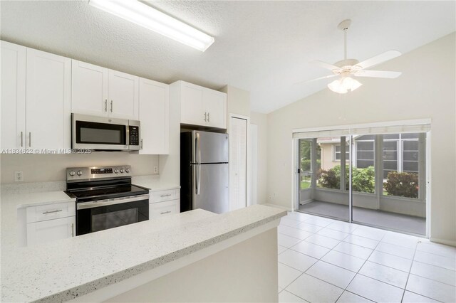 653 NW San Remo Cir, Port St Lucie, FL 34986 - kitchen featuring stainless steel appliances, lofted ceiling, white cabinets, light stone counters, and light tile patterned floors
