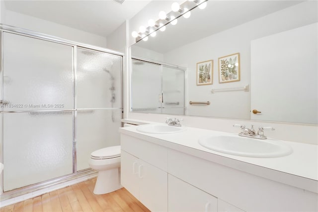 653 NW San Remo Cir, Port St Lucie, FL 34986 - bathroom featuring double vanity, a shower with door, and wood finished floors