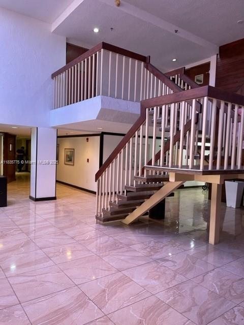 17890 W Dixie Hwy Unit 219, Miami, FL 33160 - stairs with marble tiled flooring and a towering ceiling