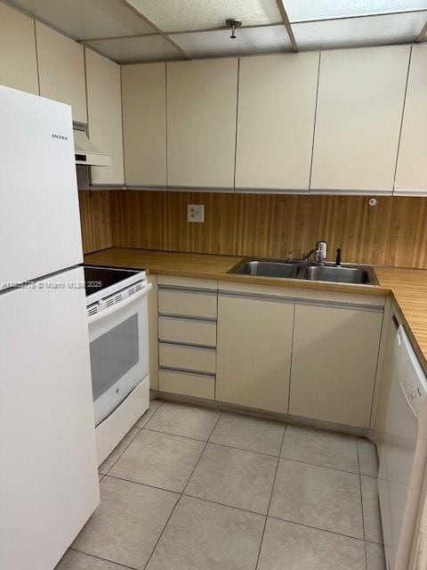 17890 W Dixie Hwy Unit 219, Miami, FL 33160 - kitchen featuring white appliances, under cabinet range hood, light tile patterned floors, a drop ceiling, and wood walls