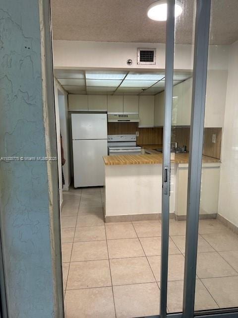 17890 W Dixie Hwy Unit 219, Miami, FL 33160 - kitchen featuring white appliances, light tile patterned flooring, exhaust hood, and a peninsula