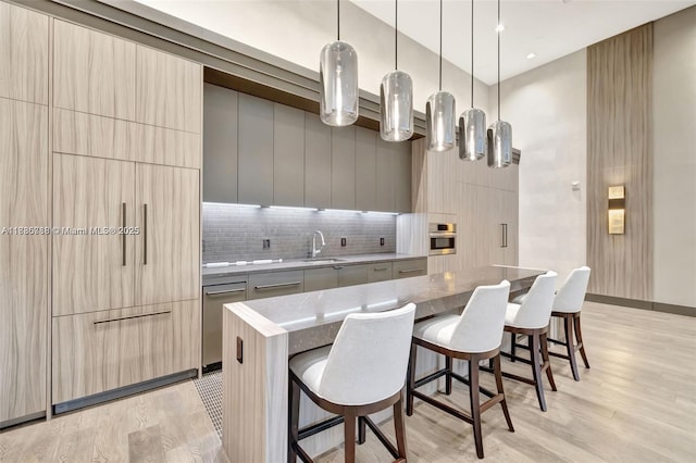 4100 Island Blvd Unit 701, Aventura, FL 33160 - kitchen with modern cabinets, a breakfast bar area, a kitchen island, tasteful backsplash, and light wood-type flooring