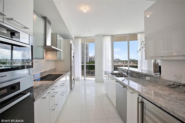 4100 Island Blvd Unit 701, Aventura, FL 33160 - kitchen with modern cabinets, wall chimney range hood, wine cooler, stainless steel appliances, and light stone countertops