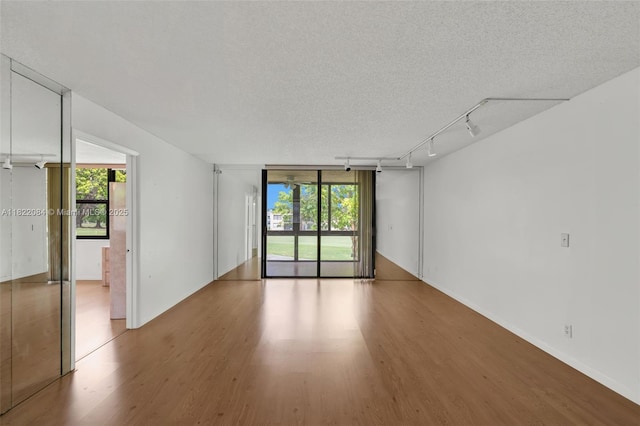 7331 NW 18th St Unit 205, Margate, FL 33063 - spare room with wood finished floors, healthy amount of natural light, a textured ceiling, and rail lighting