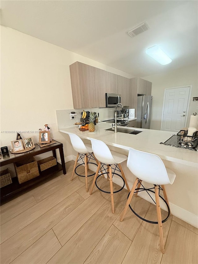 15260 SW 91st Ln, Miami, FL 33196 - kitchen featuring stainless steel appliances, a kitchen breakfast bar, modern cabinets, a peninsula, and light countertops