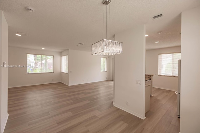 1326 Majesty Ter, Weston, FL 33327 - empty room featuring a smoke detector, a textured ceiling, light wood finished floors, a chandelier, and healthy amount of natural light