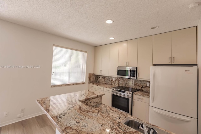 1326 Majesty Ter, Weston, FL 33327 - kitchen featuring appliances with stainless steel finishes, a textured ceiling, light wood-type flooring, recessed lighting, and light stone countertops