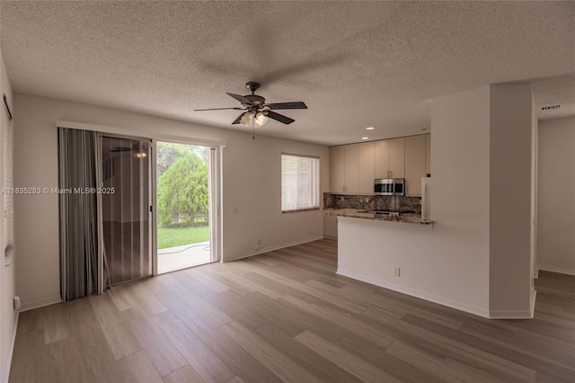 1326 Majesty Ter, Weston, FL 33327 - unfurnished living room featuring light wood-type flooring, a ceiling fan, and a textured ceiling