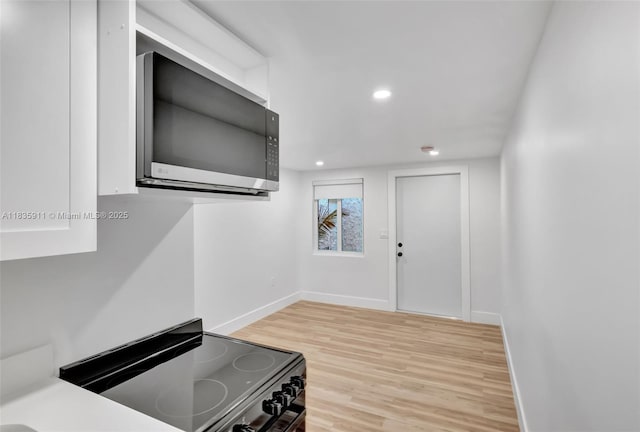 1260 SW 4th St, Miami, FL 33135 - kitchen featuring black range with electric cooktop, stainless steel microwave, light wood-type flooring, and recessed lighting