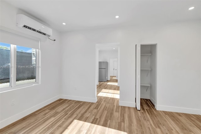 1260 SW 4th St, Miami, FL 33135 - unfurnished bedroom with a wall unit AC, freestanding refrigerator, light wood finished floors, recessed lighting, and a closet
