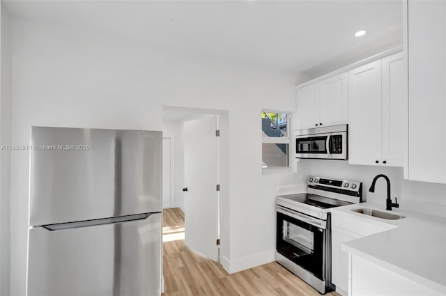 1260 SW 4th St, Miami, FL 33135 - kitchen featuring appliances with stainless steel finishes, light countertops, light wood-type flooring, white cabinets, and recessed lighting