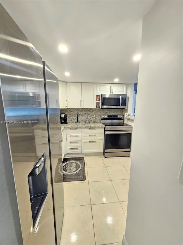 200 172nd St Unit 217, Sunny Isles Beach, FL 33160 - kitchen featuring stainless steel appliances, white cabinets, light tile patterned flooring, decorative backsplash, and light stone counters