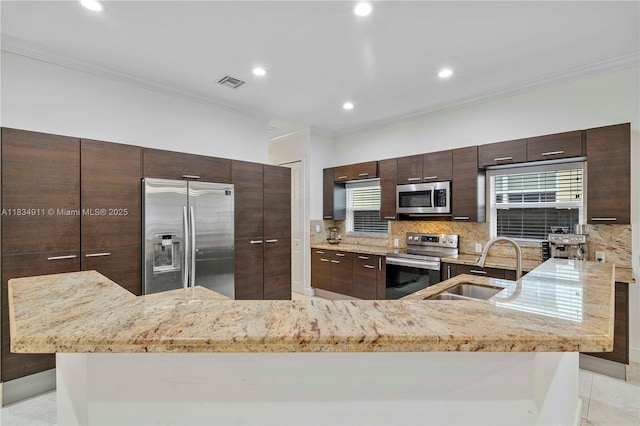 217 SW 11th St, Fort Lauderdale, FL 33315 - kitchen with appliances with stainless steel finishes, crown molding, backsplash, light stone countertops, and dark brown cabinets