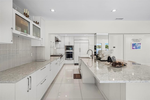 1930 NE 193rd St, Miami, FL 33179 - kitchen with modern cabinets, under cabinet range hood, stainless steel oven, white cabinets, and light tile patterned floors