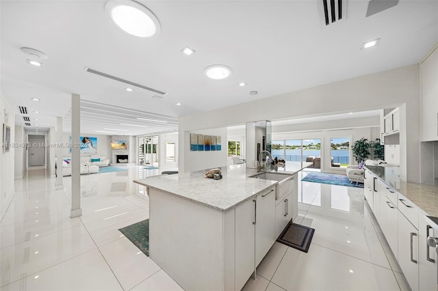 1930 NE 193rd St, Miami, FL 33179 - kitchen featuring open floor plan, modern cabinets, a large island with sink, white cabinetry, and light stone countertops