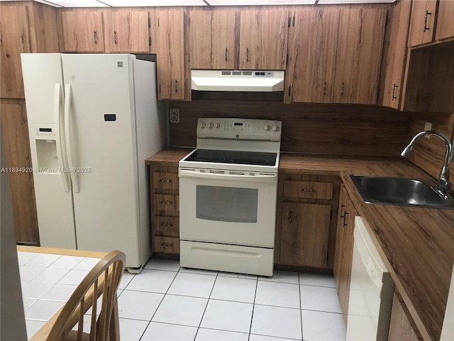1101 Colony Point Cir Unit 206, Pembroke Pines, FL 33026 - kitchen featuring under cabinet range hood, white appliances, light tile patterned floors, brown cabinetry, and tile counters