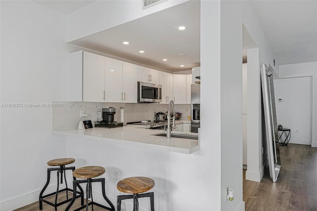 11532 SW 148th Path, Miami, FL 33196 - kitchen with stainless steel appliances, decorative backsplash, a breakfast bar, wood finished floors, and recessed lighting